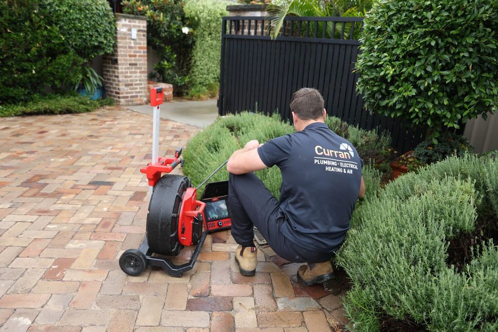 Curran technician reviewing live CCTV drain camera footage at a local home