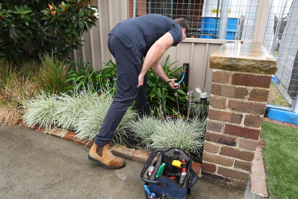 Curran plumber checking water pressure at an outdoor meter